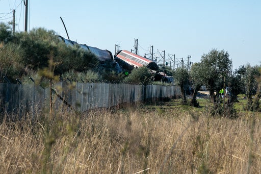 Rescue workers at a train crash site in central Spain, with debris and emergency vehicles visible.